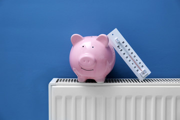 Piggy bank on radiator with thermometer. Saving  heating in winter