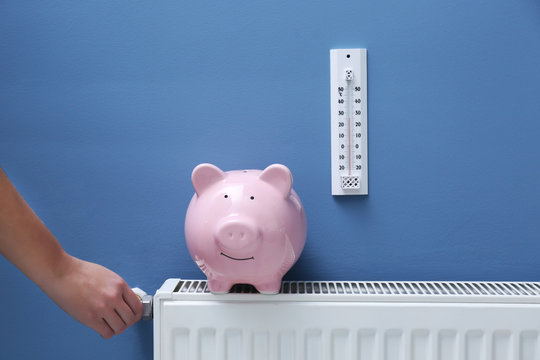 Hand adjusting the temperature on radiator. Saving  heating in winter