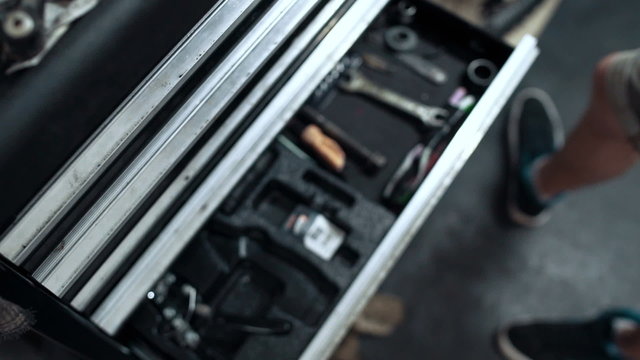 	Mechanic is taking tool from tool box, pan, close up