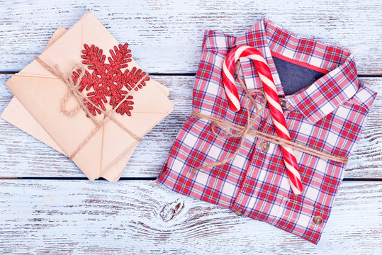 Checkered shirt with Christmas gifts on white wooden background, close up