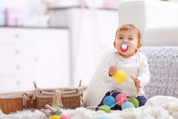 Naklejka premium Sweet baby girl with a soother playing on a floor