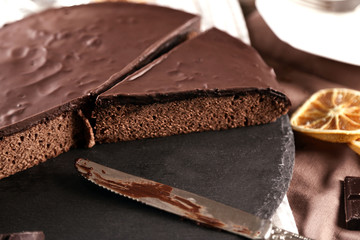 Sliced chocolate frosting cake on wooden table