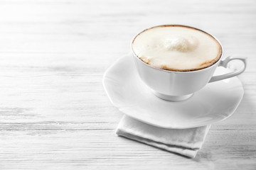 Cup of cappuccino with frost on light wooden table