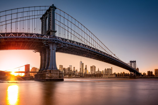 Manhattan Bridge framing New York skyline at sunset. The use of a fisheye effect enhances the perspective.