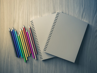 Plakat color pencil on checked notebook on wood background