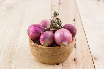 Group of red onion in the wood bowl.