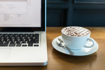 Hot art Latte Coffee in a cup and laptop on wooden table.