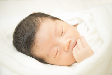 タオルに包まれて眠る新生児のアップ