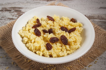 Cooked millet groats on white plate, healthy food and nutrition