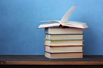 Pile of books on a wooden table.