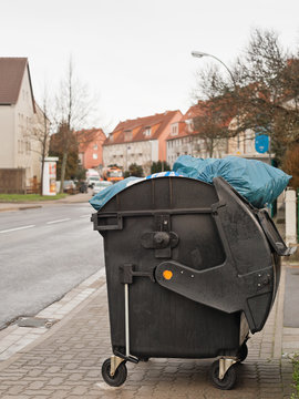 Blaue M&uuml;lls&auml;cke gucken aus einem offenen fahrbarem M&uuml;llcontainer