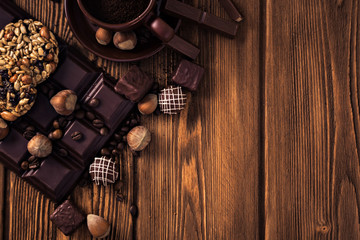 Roasted coffee beans, chocolate, muesli, candy, nuts and cup on the wooden background