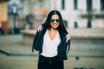 Obraz premium Young fashion brunette woman in sunglasses with jacket on city street