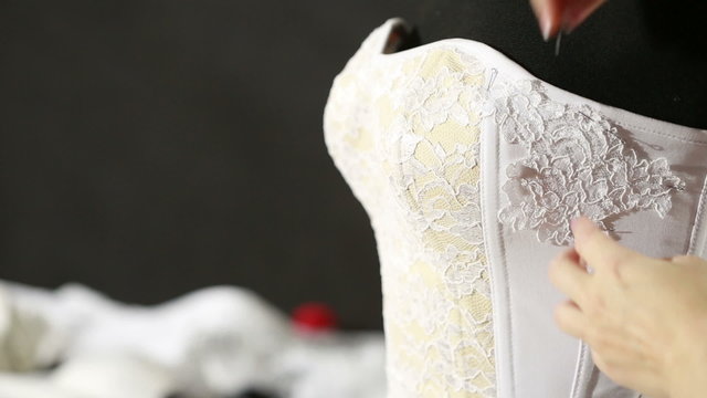 Corset lacing in the manufacturing plant underwear. Manufacture of underwear, tying lace corset seamstress. white corset