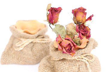 Bouquet of dried withered roses in sackcloth bag on white backgr