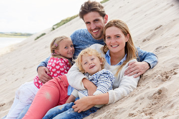 Portrait Of Family Lying In Sand Dunes Together