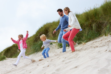 Family On Beach Vacation Running Through Dunes