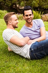 Happy gay  couple lying on grass 