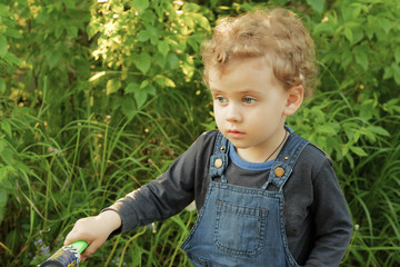 Little  CUrly Blond  boy playing with stripped toy cat near the window