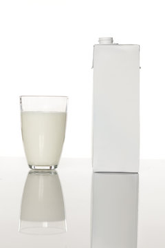 glass of milk next to cardboard packaging of milk