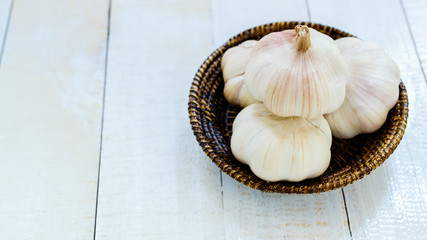 garlic in basket on white wooden background