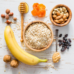 Granola bars ingredients on white wood background