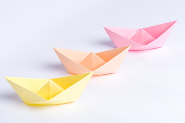 Three origami paper ships in pastel colors isolated on white