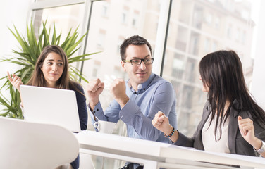 Fototapeta premium Young successful business people interacting, discussing and sharing ideas in bright modern office with clenched fists. Focus on man in the middle. Teamwork concept