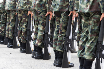 Soldiers stand holding a gun.