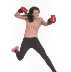 Junge Frau mit Boxhandschuhen macht einen Sprung nach vorne 
