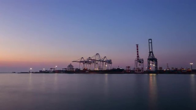 Container Cargo freight ship with working crane bridge in shipyard at dusk for Logistic Import Export background