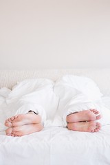  Bare feet of gay couple out from the blanket