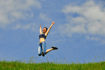 Beautiful and happy girl jumps high on grass