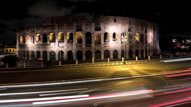 Time-Lapse notturno delColosseo a Roma con la scia luminosa dei veicoli in transito.