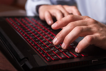 Laptop keyboard with fingers of a   working man.