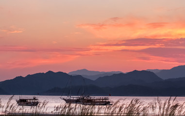 Sunset over the sea bay with mountains in the background.