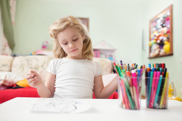 Portrait of child blonde girl drawing at home in her room