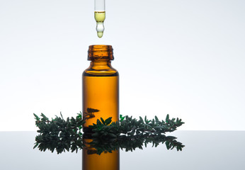 Essential oil with thyme leaves, in amber glass with dropper, horizontal. - 102817532
