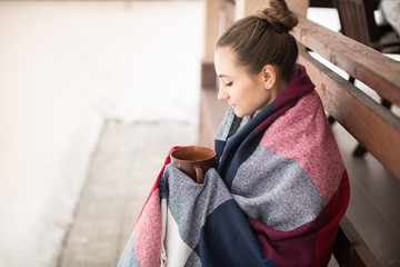 Girl in rug drinks hot tea in winter