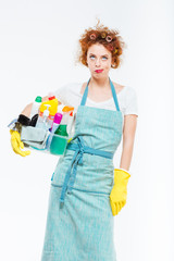 Irritated woman in yellow gloves holding box with cleansers