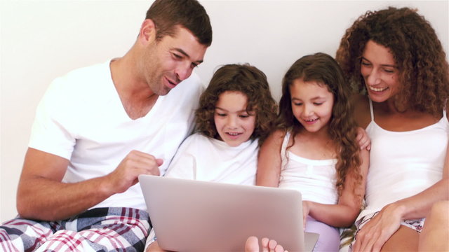 Cute family using laptop computer on their bed