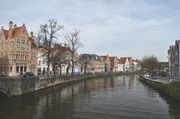 Panoramic view along one of the canals in Bruges Belgium flanked by trees and characteristic old buildings 