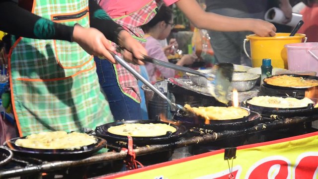 Thai people cooking Fried mussel with egg and crispy flour or Oyster omelette for sale people in market fair in annual festival of Wat Lam Pho in Nonthaburi, Thailand.