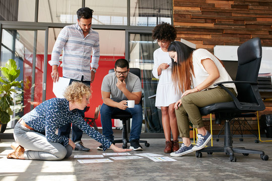 Creative people looking at project plan laid out on floor