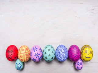 bright, colorful painted eggs for Easter, laid out in a row border place for text  on wooden rustic background top view close up
