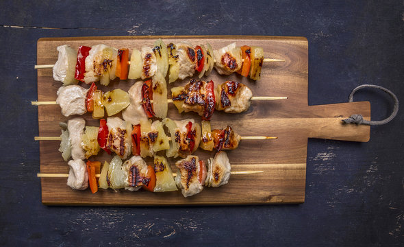roasted kebabs on a cutting board with sauce on wooden rustic background top view close up