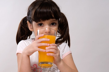 Portrait of little girl drinking a glass of orange juice