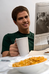 Young man having breakfast and reading the newspaper