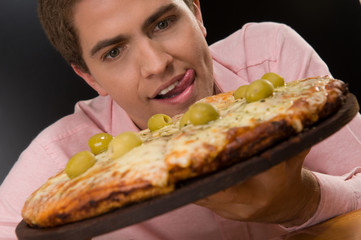 Excited young man eating pizza