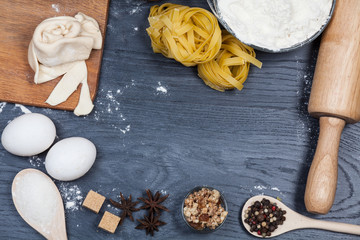 Ingredients for baking dough including flour, eggs, milk, whisk and rolling pin on wooden rustic background, empty space for text, top view